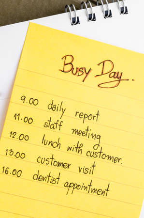 Busy day and plan in yellow stick note on calendar.の写真素材