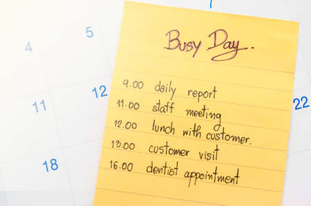 Busy day and plan in yellow stick note on calendar.の写真素材