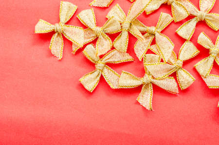 Gold bow ribbons on red paper background.の写真素材