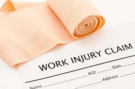 Work injury claim form showing business insurance concept and medical bandage roll.