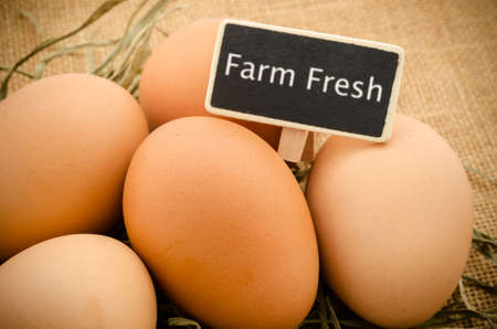 Fresh eggs with farm fresh wooden tag on the sack background.の写真素材