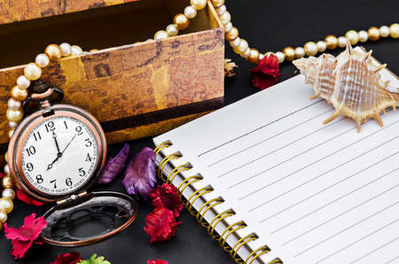 Open diary and vintage pocket watch with decorate on black background.の写真素材