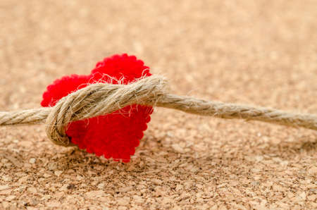 Red heart with a bundle rope on wooden boardの写真素材