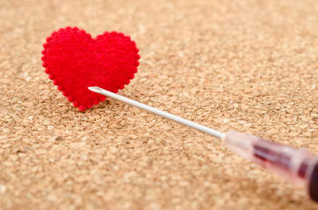 Red heart and needle syringe on wooden background.の写真素材