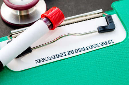 Sample blood in tube for test and New patient information sheet in file with stethoscope on black background.の写真素材