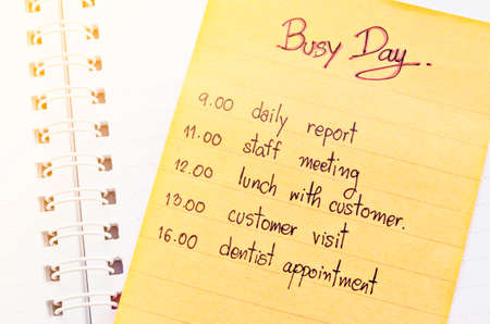 Busy day appointment business schedule in note paper on open diary.