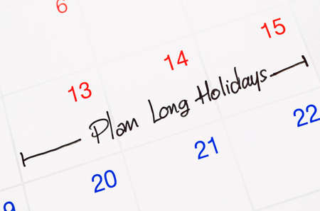 Plan long holidays word written on a white calendar page to remind.