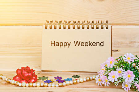 Happy weekend text on note paper with flower and morning sunlight in wooden room.の写真素材