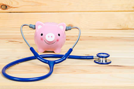 Piggy Bank and Stethoscope in wooden room.の写真素材