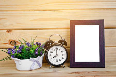 Blank wood photo frame and alarm clock with flower on wooden room, Save clipping path.の写真素材