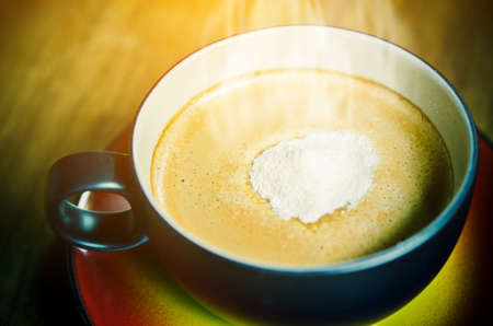 Creamer on top a cup of hot coffee on wooden background.の写真素材
