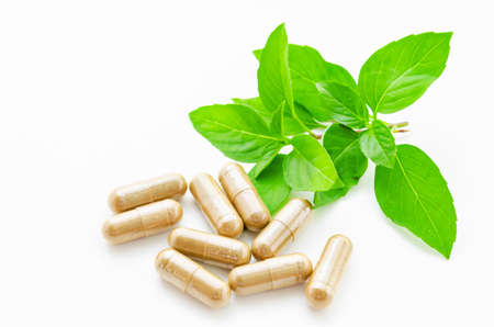 herbal drug capsule and green leaf on white background.の写真素材