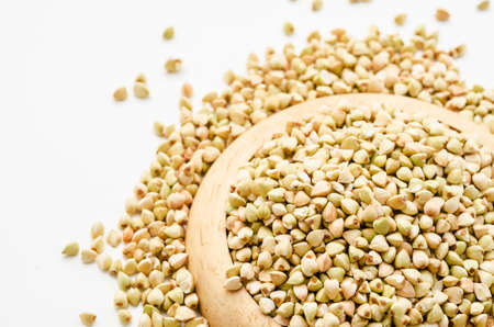 Uncooked buckwheat in wooden dish. premium buckwheat groats on white backgroundの写真素材