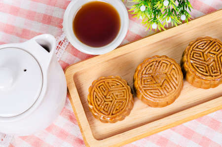 Festival moon cake and hot tea - Chinese cake on tablecloth.