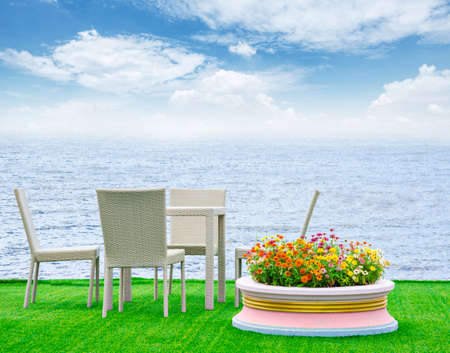 Deck Chairs and flower pot on green grass byside beach sea with blue sky.の写真素材