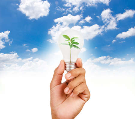 Hand holding LED bulb on blue sky background