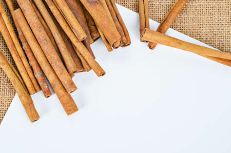 Cinnamon sticks with empty space of white paper for your text or message on sack background.の写真素材