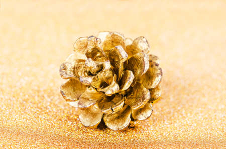 Gold pine cones for christmas on abstract golden backgroundの写真素材