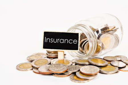 Insurance fund tag with coins in glass jar on white background.