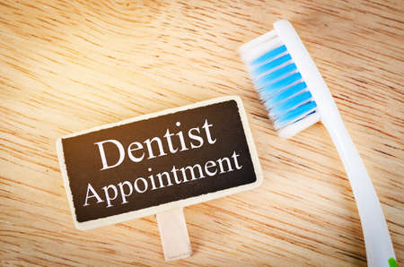 Dentist appointment tag on wooden with toothbrush.の写真素材