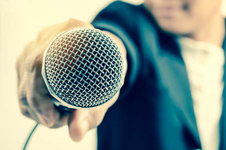 Man in business suit holding a microphone conducting a business interview with lighting.の写真素材