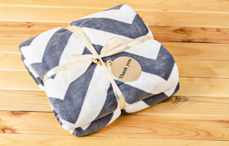 Blanket with ribbon and Thank you tag gift on wooden background.の写真素材