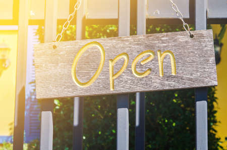 Wood open sign board hang on door of coffee shop with lighting in the morning.の写真素材
