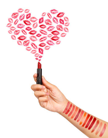 Female hand testing different lipsticks, showing swatches and lipstick mark kiss heart shape on white background.の写真素材