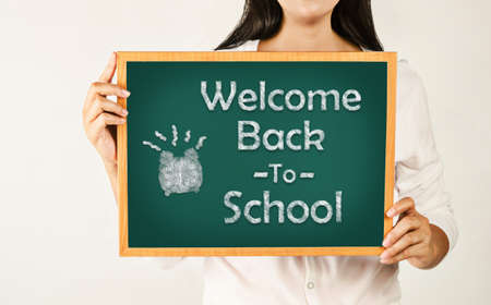 Woman holding Welcome back to school on green board.の写真素材