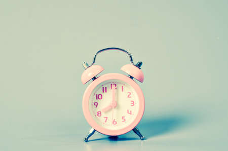 Pink alarm clock with shadow on gray background. Vintage style.の写真素材