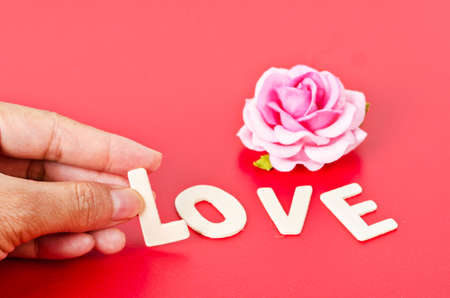 Hand arrange wood letters as love word on red background.の写真素材