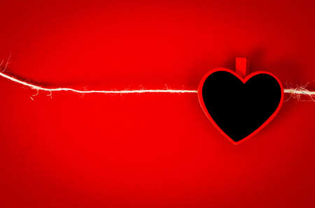 Heart from wooden tag with rope in red background.の写真素材