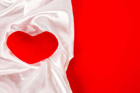 Red heart with white elegant fabric on red background, With empty space.の写真素材