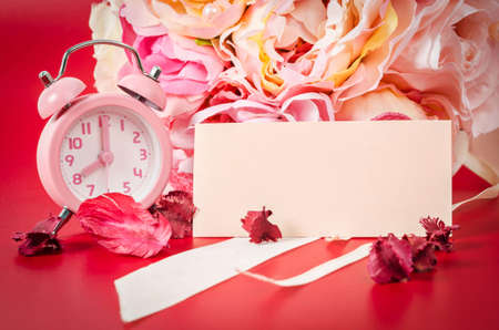 Blank card and Pink alarm clock with bouquet pink rose on red background.の写真素材