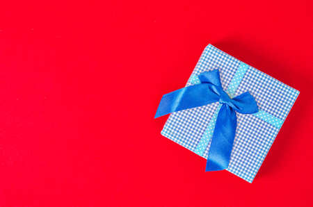 Blue gift box on red background with empty space for your text or message.の写真素材