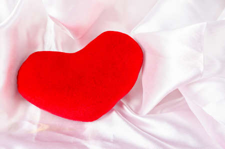 Red heart on elegant white fabric background.の写真素材