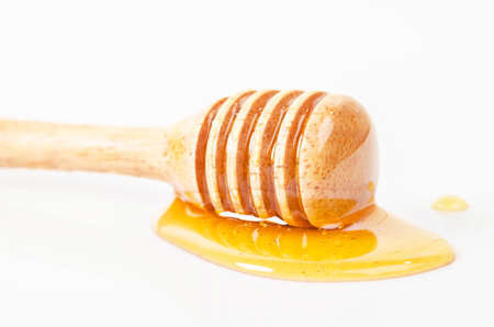 Honey dripping with honey stick isolated on a white background.の写真素材