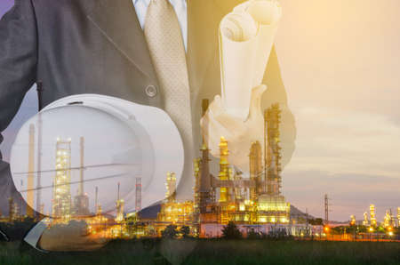 engineering man and safety helmet standing against oil refinery plant in heavy petrochemical industrial estate.の写真素材