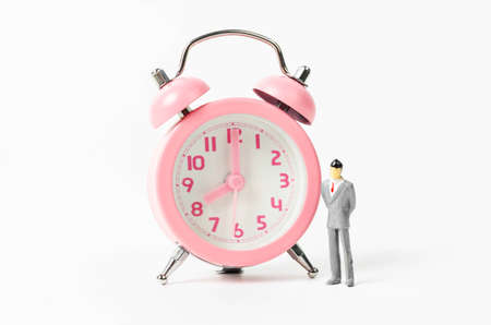 Vintage pink alarm clock and businessman miniature on white background. Working time concept.
