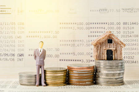 Miniature businessman stand on the stack of coins on book bank background with light. Financial concept.の写真素材