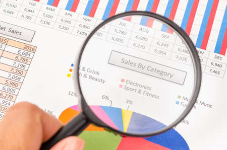 Hand of businesswoman holding magnifying glass on sales by category report.の写真素材
