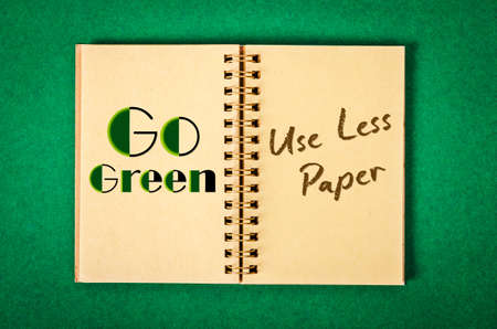 Go Green. Use Less Paper in recycle paper notebook on green background.の写真素材