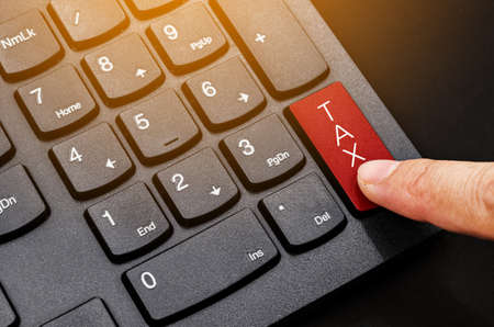 Taxes concept. Number button on computer keyboard with tax button and finger.