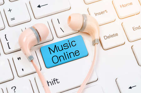 Music online Earphones on white computer keyboard.