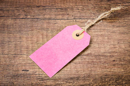 Blank pink paper tag price on wooden background.の写真素材