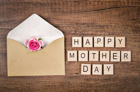 Happy mother day write on wooden cube with pink rose on wooden background.の写真素材