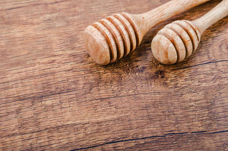 Wooden honey dippers on wooden background.の写真素材