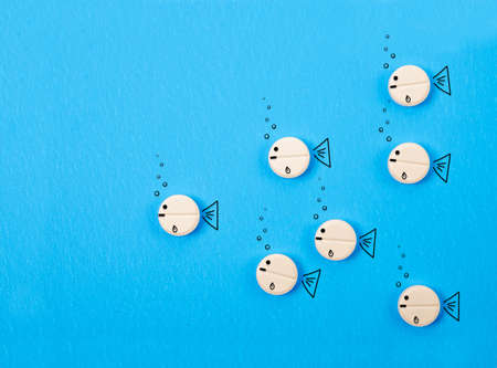 White pills with draw fish on blue background.の写真素材