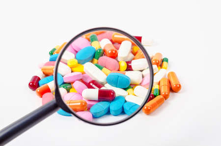 pills under magnifying glass on white background.の写真素材