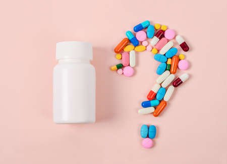 Pills or capsules as a question mark and white plastic bottle.の写真素材